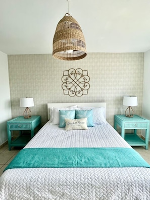 A bedroom with a bed, two nightstands, a hanging light fixture, and a decorative wall piece. - Beachfront 3-Bedroom Apartment with Breathtaking Views in Luquillo (Luquillo)