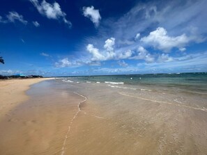 A beach with clear skies and calm waters. - Beachfront 3-Bedroom Apartment with Breathtaking Views in Luquillo (Luquillo)