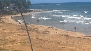 A beach with palm trees, a dome structure, and people in the water. - Beachfront 3-Bedroom Apartment with Breathtaking Views in Luquillo (Luquillo)