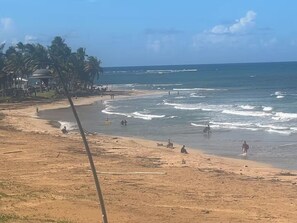A beach with palm trees, a dome structure, and people in the water. - Beachfront 3-Bedroom Apartment with Breathtaking Views in Luquillo (Luquillo)