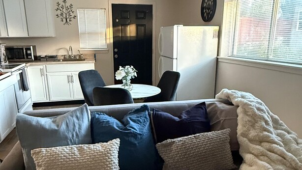 Un espacio habitable compacto con sofá, mesa de comedor y zona de cocina.