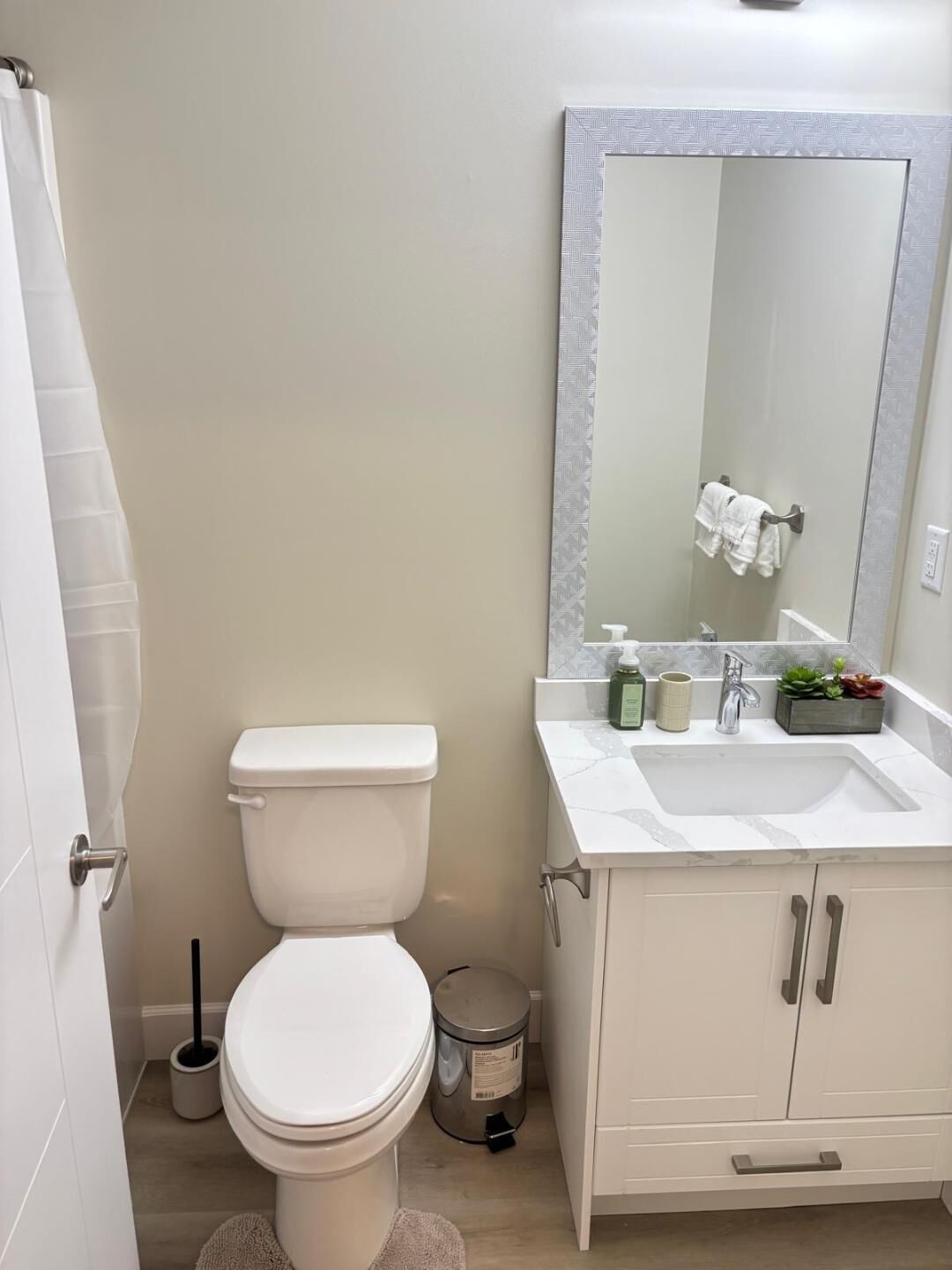 Un baño con inodoro, lavabo, espejo y armarios.