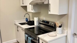 Una cucina compatta con mobili bianchi, un fornello nero e un lavandino in acciaio inossidabile.