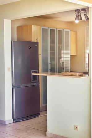 Eine Küche mit einem Edelstahl-Kühlschrank, einem Holzkasten und einem Schrank mit Glastür.