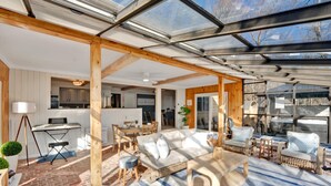 A spacious living area with a glass ceiling, wooden beams, a sofa set, and a dining area. - Lake Views | Tub Sauna Kayak Bike Fire Pit EV (Albrightsville)