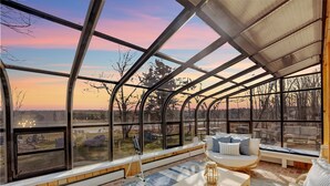 A spacious room with large windows, a cozy seating area, and a view of the outdoors. - Lake Views | Tub Sauna Kayak Bike Fire Pit EV (Albrightsville)