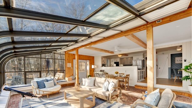 A spacious living area with a large glass ceiling, wooden beams, and a cozy seating arrangement. - Lake Views | Tub Sauna Kayak Bike Fire Pit EV (Albrightsville)
