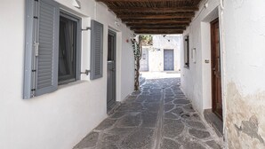 A narrow stone-paved alleyway with white walls and shutters, leading to a blue door. - El. Passo Cycladic Alley Studio • Paros by ΜΡS (Paros)