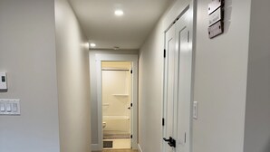 Ein Flur mit Holzboden, weißen Wänden und einer Tür zu einem Badezimmer.