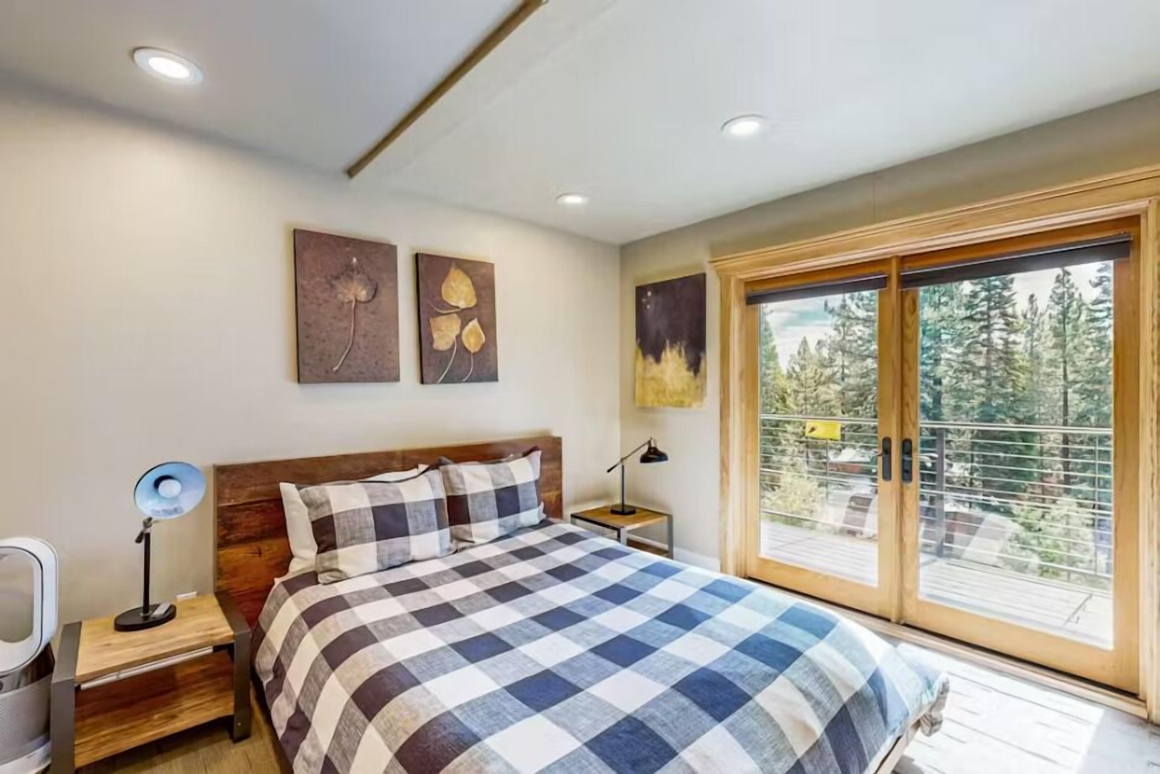 A bedroom with a checkered bedspread, wooden headboard, bedside tables with lamps, and artwork on the walls.