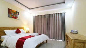 A hotel room with a bed, a nightstand, a lamp, a wooden bench, and a large window with curtains. - Lotus Canggu (Tibubeneng)