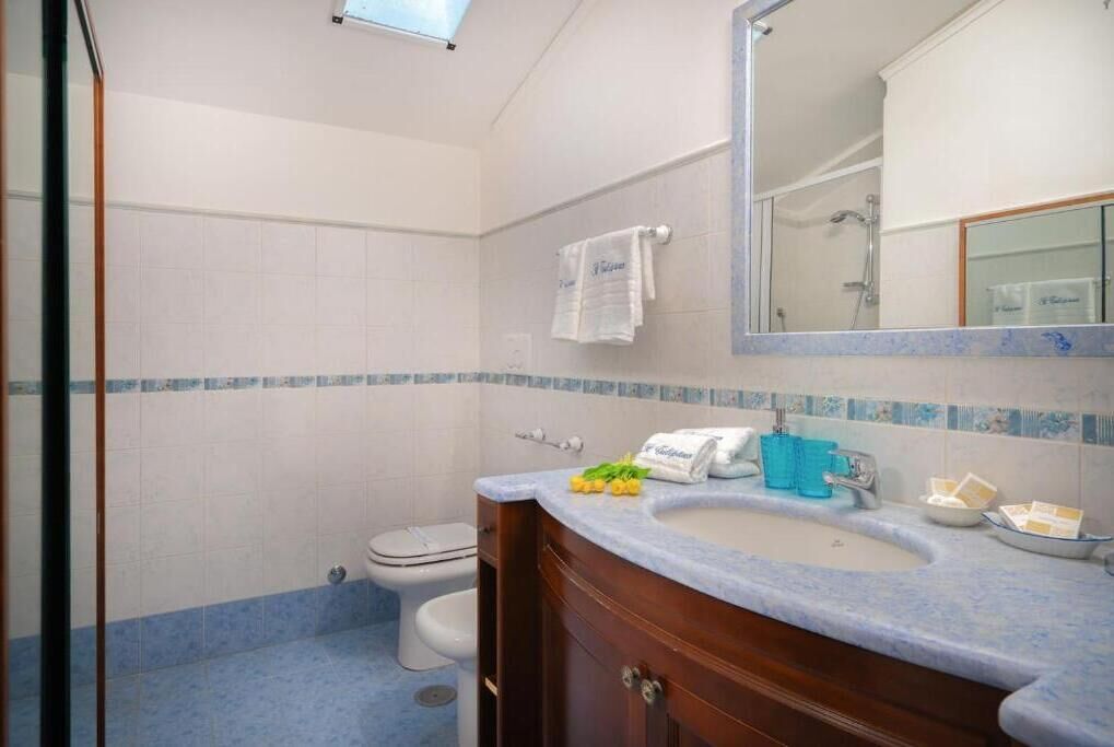 A bathroom with a white toilet, a sink with a blue countertop, and a mirror above the sink.