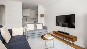 Ein modernes Wohnzimmer mit einem grauen Sofa, einem Couchtisch und einem Fernseher.