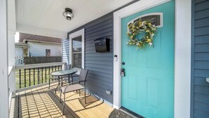 A porch with a teal door, a small table, and two chairs. - Uptown Vibe, Downtown Location - Sleeps 6 (Indianapolis)