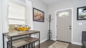 A hallway with a wooden table and chairs, a coat rack, a door, and a framed picture on the wall. - Uptown Vibe, Downtown Location - Sleeps 6 (Indianapolis)