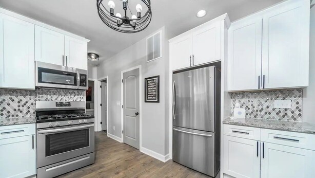 A modern kitchen with white cabinets, stainless steel appliances, and a patterned backsplash. - Uptown Vibe, Downtown Location - Sleeps 6 (Indianapolis)
