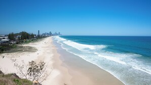 Ein Strand mit freiem Blick auf das Meer und einer Stadtansicht in der Ferne.