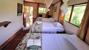 A hotel room with two beds, a large window with a view of greenery, a ceiling fan, and a mirror on the wall. - Milia Amazon Lodge (Iquitos)