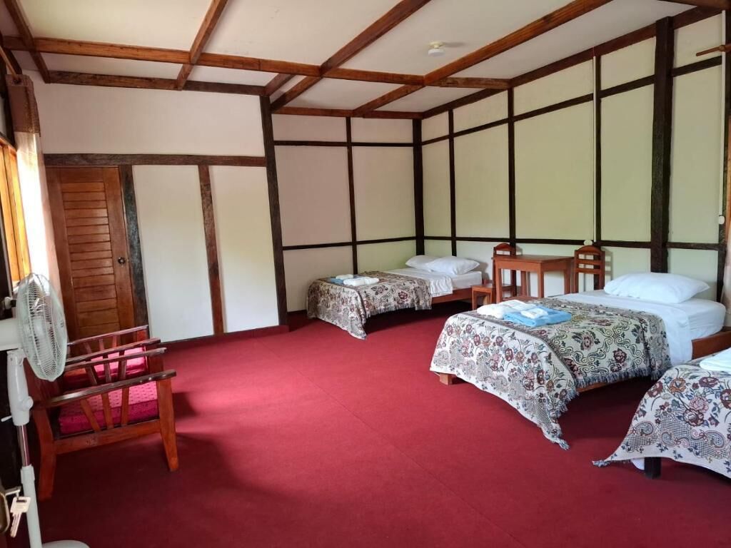 A traditional Japanese-style room with tatami flooring, a wooden ceiling, and a bed with a patterned bedspread.