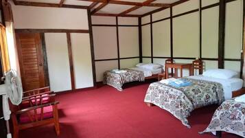 A traditional Japanese-style room with tatami flooring, a wooden ceiling, and a bed with a patterned bedspread.