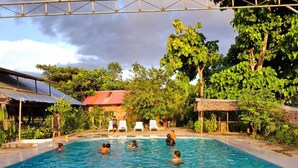 A swimming pool with steps leading into it, surrounded by lush greenery and a thatched-roof structure. - Milia Amazon Lodge (Iquitos)