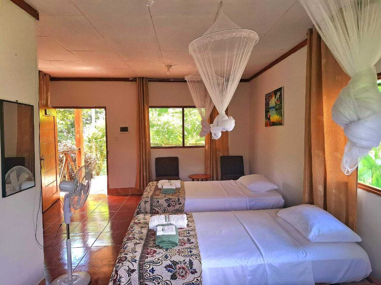 A hotel room with two beds, a sitting area, and a large window.