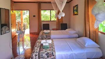 A hotel room with two beds, a sitting area, and a large window.