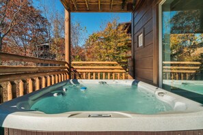 A hot tub on a wooden deck with a wooden fence and trees in the background. - VIEWS! Sleeps 22 | Pool | Theater | Game Rm | (Sevierville)