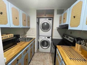 Una cocina compacta con lavadora doble, una barra de café y encimera de madera.