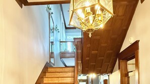 Una escalera de madera que conduce a un segundo piso, con un candelabro colgando en el techo.