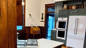 Una cocina con una isla central, hornos dobles y un refrigerador.