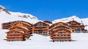 Un grupo de cabañas de madera con balcones, con una imponente montaña nevada de fondo.