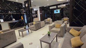 Een moderne lobby met een zwarte marmeren wand, een grote klok en een flatscreen-televisie.