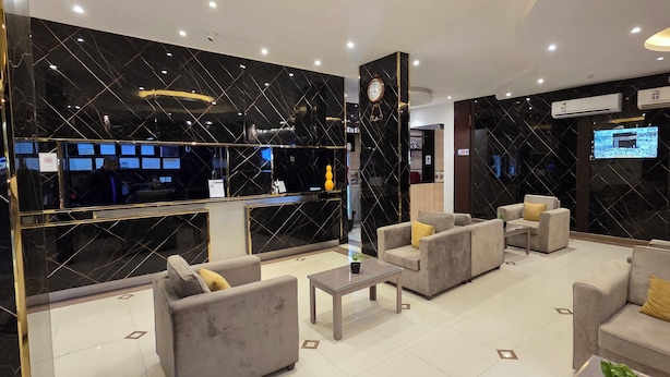 Een moderne lobby met een receptiebalie, een zithoek en een groot scherm dat content toont.