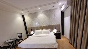 Een moderne hotelkamer met een groot bed, nachtkastjes, een stoel en een klein tafeltje.