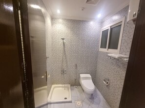 A bathroom with a shower, toilet, and a small sink. - افاق سويت المصيف للشقق المخدومة - Afaq Suite Al Massif Serviced Apartments (Riyadh)