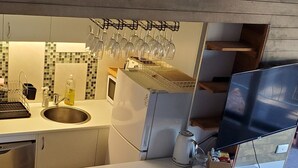 Cozinha com frigorífico embutido, pia e micro-ondas. Há um quadro na parede acima da pia.
