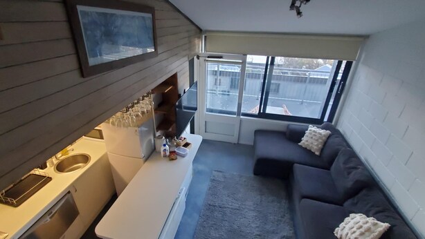 Um espaço compacto com cozinha compacta, sofá e uma janela grande que oferece vista para o exterior.