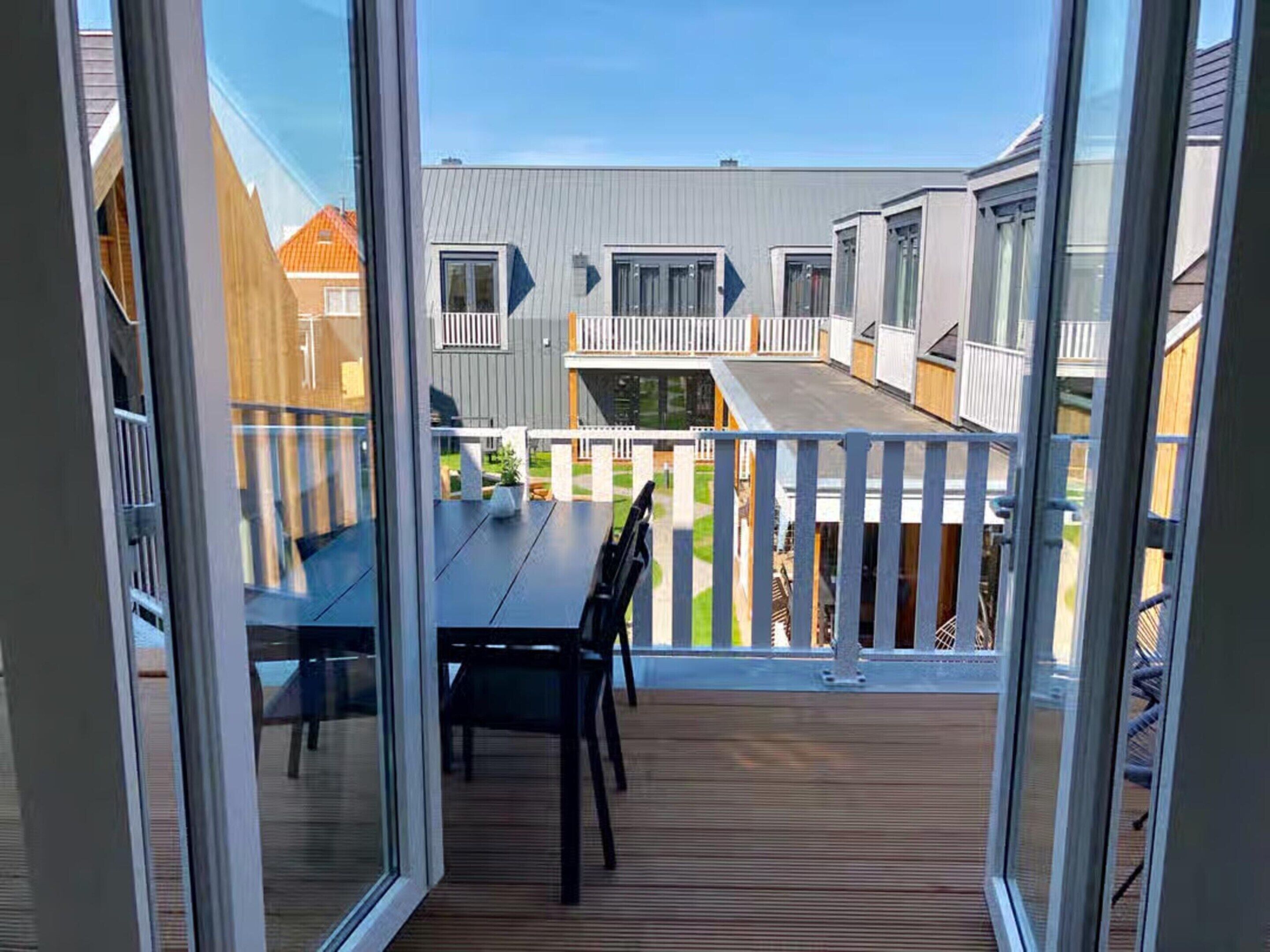 Ein Balkon mit Holzterrasse, Tisch und Stühlen.