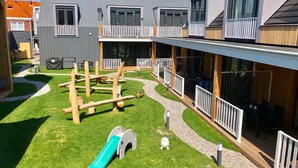 Ein modernes Gebäude mit überdachtem Außenbereich, einem Spielplatz und einer Rutsche.