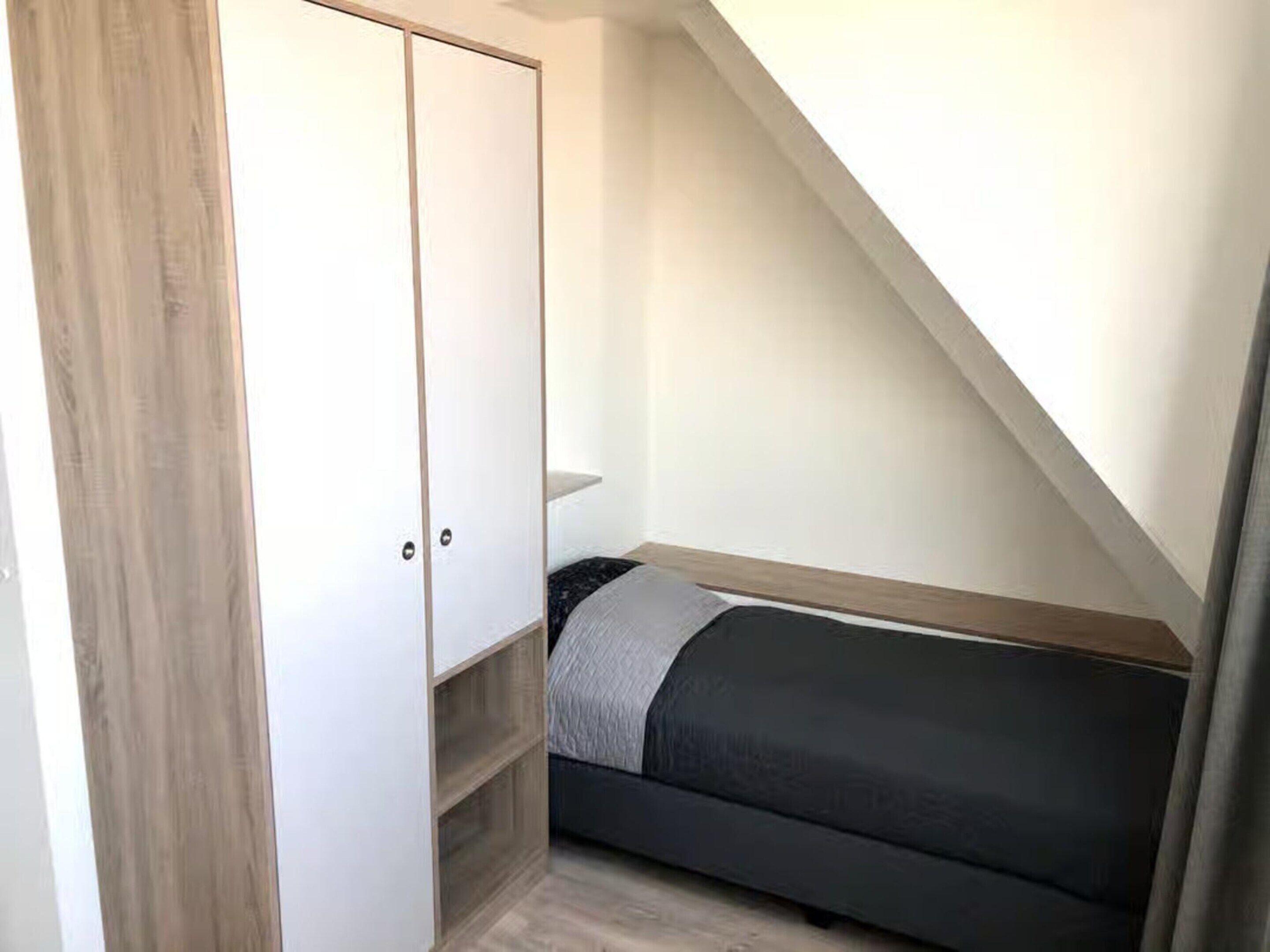 A small bedroom with a bed, a wardrobe, and a sloped ceiling.