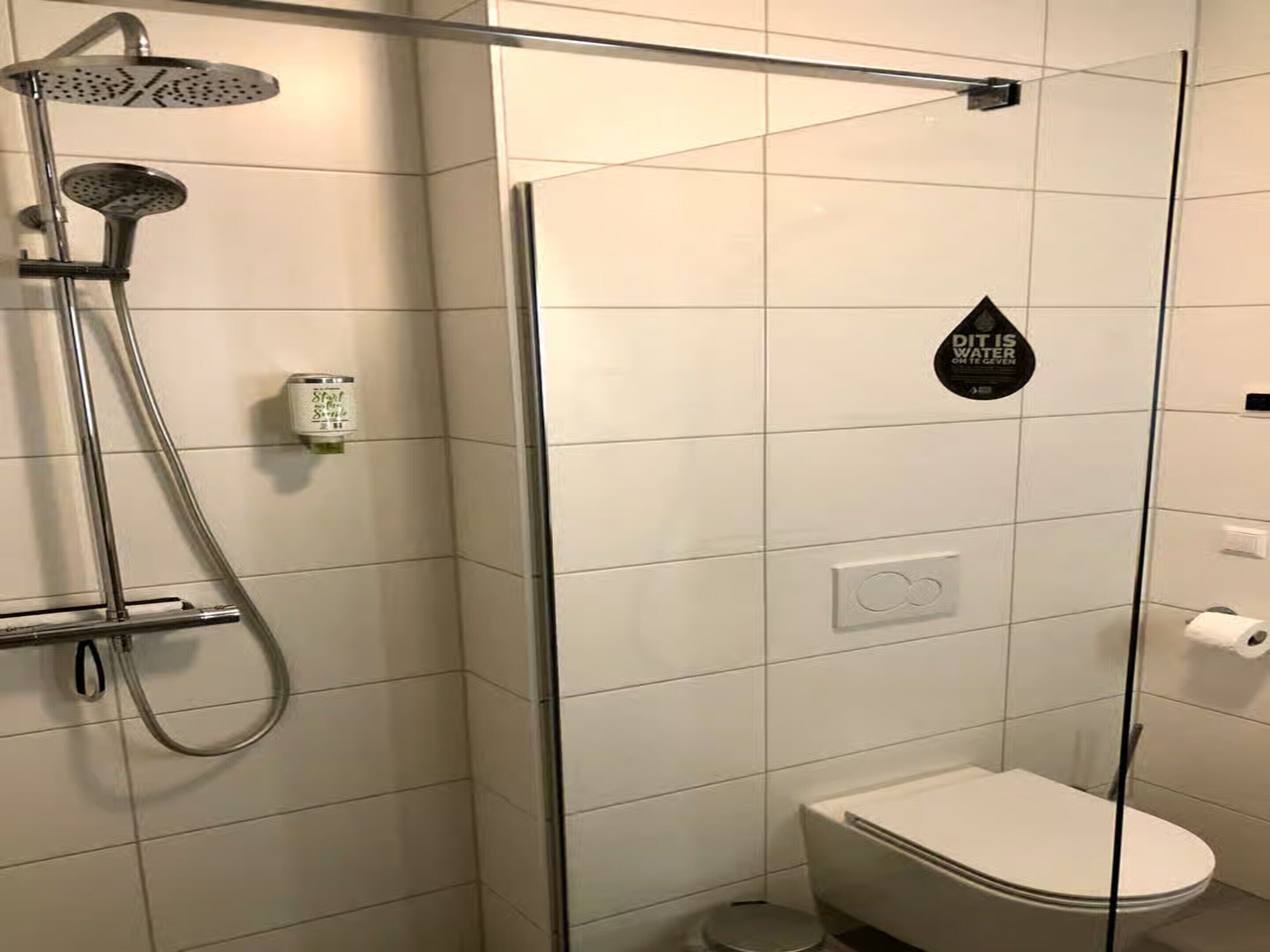 Et moderne badeværelse med bruseniche, toilet og hårtørrer.