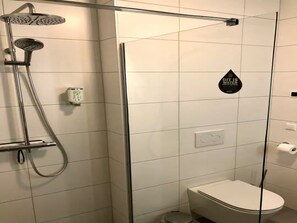 A modern bathroom with a glass-enclosed shower, a toilet, and a hand dryer. - Beautiful Lodge Located on the Church Square (Zoutelande)