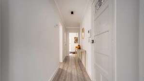 A hallway with white walls, a wooden floor, and a door on the right. - Nomads By Sta Catarina Flats - Friends (Porto)