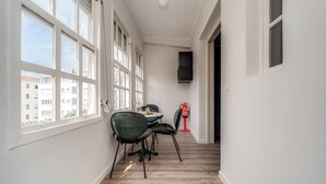 A narrow hallway with large windows, a table with chairs, and a fire extinguisher. - Nomads By Sta Catarina Flats - Friends (Porto)