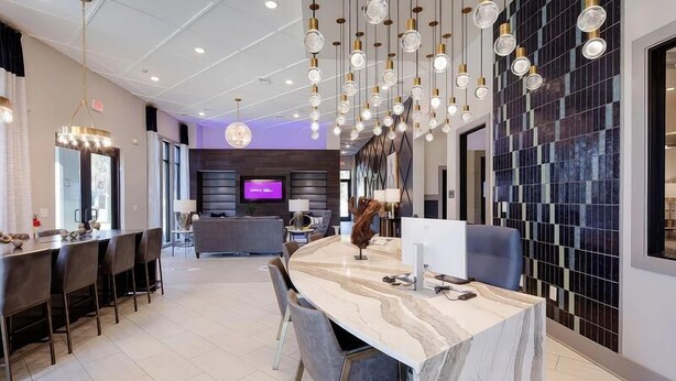 Eine moderne Hotelhalle mit einer Marmor-Rezeption, einem an der Wand befestigten Fernseher und einer Sitzecke mit Sesseln und einer Couch.