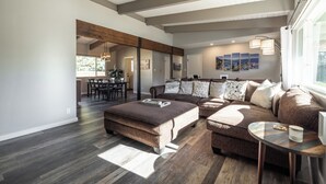 A spacious living room with a large sectional sofa, a wooden coffee table, and a dining area with a table and chairs. - Beautiful Tahoe Keys Home: Family and Pet Friendly (South Lake Tahoe)