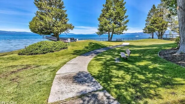 A pathway leading to a bench by a lake with trees and a clear sky. - Beautiful Tahoe Keys Home: Family and Pet Friendly (South Lake Tahoe)
