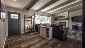 A spacious living area with a dark wooden floor, a large window, and a fireplace. - Beautiful Tahoe Keys Home: Family and Pet Friendly (South Lake Tahoe)