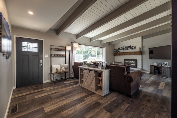 A spacious living area with a dark wooden floor, a large window, and a fireplace. - Beautiful Tahoe Keys Home: Family and Pet Friendly (South Lake Tahoe)